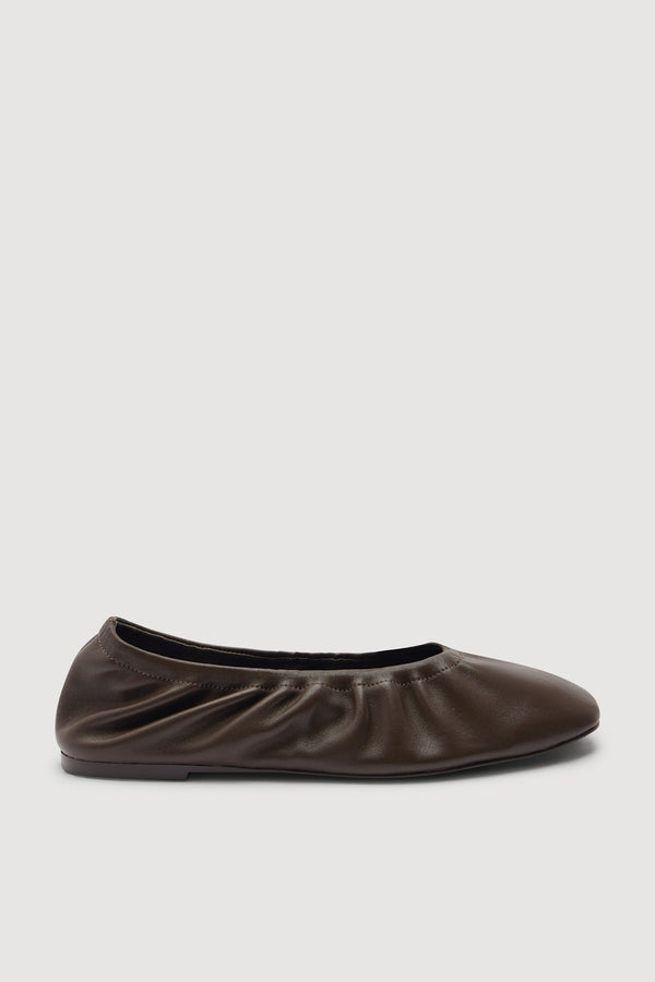 A single women's ballet flat shoe in a deep brown colour, shown from a side profile view against an off-white background.
